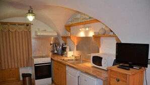 A compact kitchen with a stove, microwave, sink, and a small refrigerator.