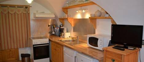 A compact kitchen with a stove, microwave, sink, and a small refrigerator.
