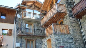 A multi-story building with wooden balconies and stone walls.