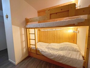 Ein Stockbett mit einer Leiter, Holzwänden und einem weißen Bettbezug.