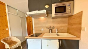 Eine kompakte Küchenzeile mit Mikrowelle, Backofen, Spüle und kleinem Kühlschrank.