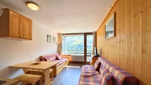 Ein gemütliches Blockhaus-Interieur mit einem Holzespeisetisch, Bänken und einer Couch mit Karomuster.