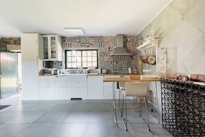 A modern kitchen with white cabinets, a patterned backsplash, and a large window.