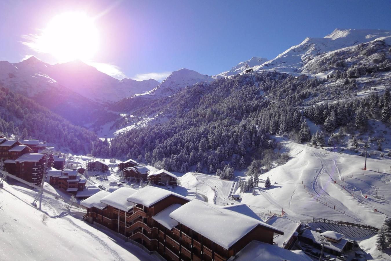 Een besneeuwde bergdorp met houten gebouwen en skipistes.