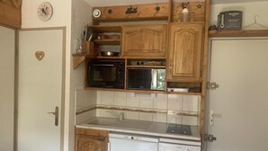 A compact kitchen with wooden cabinets, a microwave, a dishwasher, and a small countertop. - 300m from shops, 3rd floor, view mountain, balcony, tv, ski locker, 25m², Les Menuires (Les Menuires)