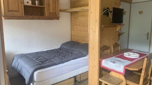 A compact room with a bed, a small table, and a television. - 300m from shops, 3rd floor, view mountain, balcony, tv, ski locker, 25m², Les Menuires (Les Menuires)