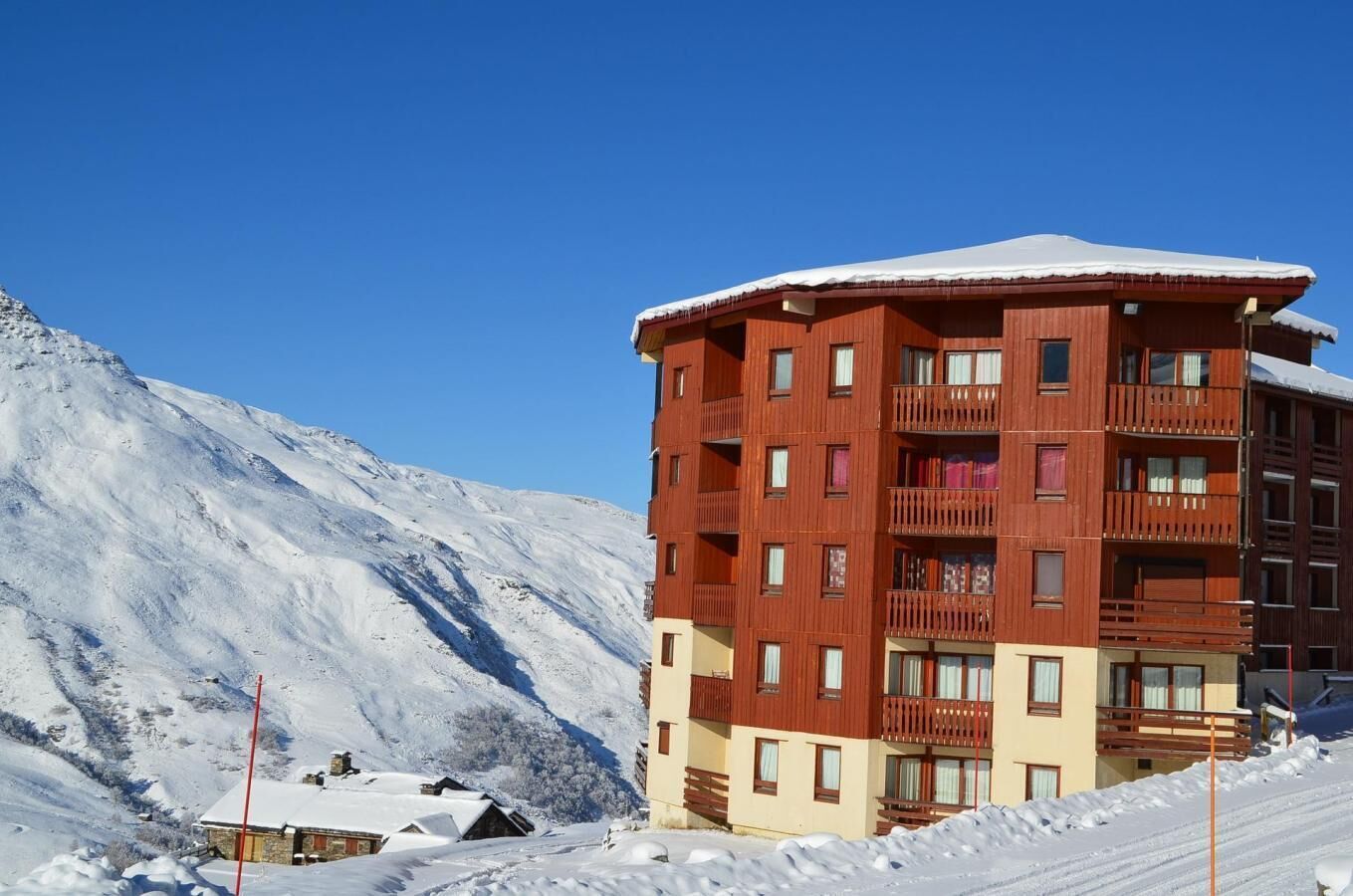 A multi-story hotel with balconies, set against a snowy mountain backdrop.