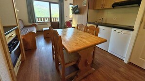 A compact kitchen with wooden cabinets, a dining table, and a built-in oven.