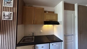 A compact kitchen with wooden cabinets, a black countertop, a built-in dishwasher, and a white door.