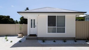 Een gelijkvloers huis met een voordeur, een garagepoort en een groot raam.