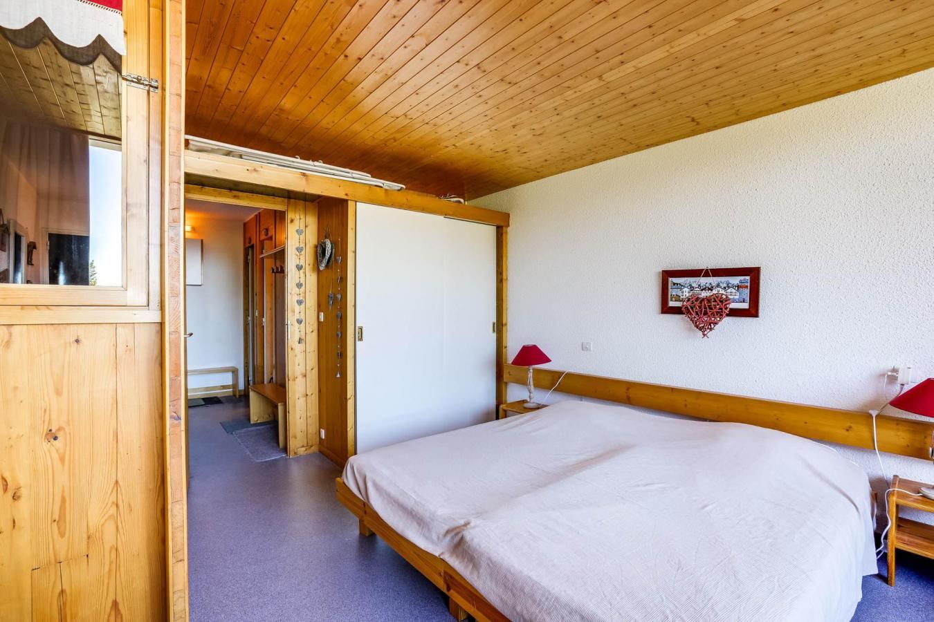 Una habitación de madera con una cama, una lámpara roja y un cuadro en la pared.