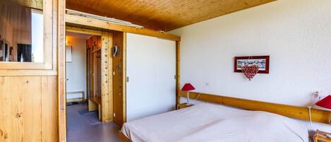 Una habitación de madera con una cama, una lámpara roja y un cuadro en la pared.