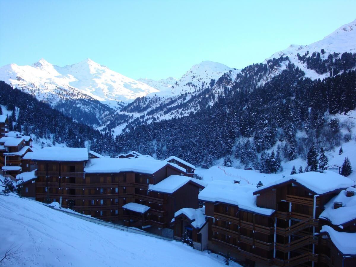 Une station de montagne enneigée, avec des bâtiments en bois et une piste de ski.