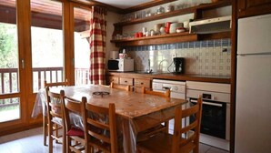 Eine Küche mit einem Holztisch, Stühlen, einer Mikrowelle, einer Kaffeemaschine und einem Kühlschrank.