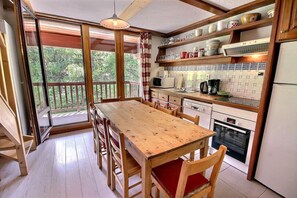 A kitchen with a wooden table and chairs, a microwave, and a refrigerator.