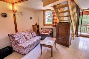 A cozy living room with a patterned sofa, a small table, and a wooden cabinet.