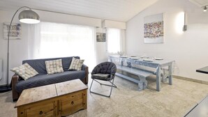 A cozy living room with a sofa, a chair, a wooden table, and a dining area with a bench and table set.