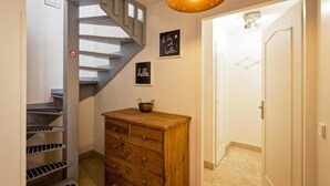 A staircase with a metal railing, a wooden dresser with drawers, and two signs on the wall.