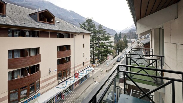 A multi-story building with balconies, a ski lift, and a mountain backdrop.