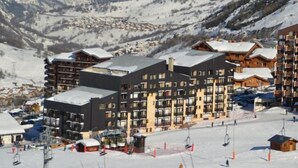 Une station de ski comprenant plusieurs bâtiments, dont un grand chalet et plusieurs autres structures plus petites.