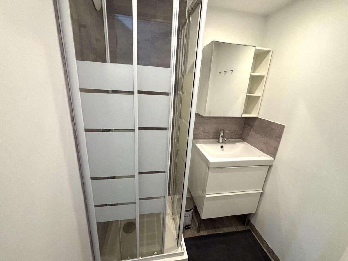 Une petite salle de bain avec une douche, un lavabo et un miroir.