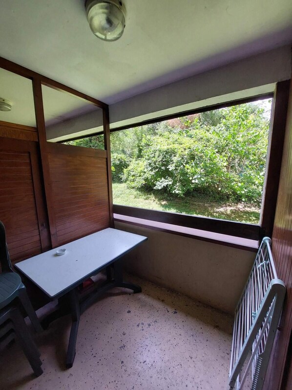 A small room with a single table and chair, a radiator, and a large window offering a view of greenery outside. - 2nd floor, balcony, tv, 28m², Brides Les Bains (Brides-les-Bains)