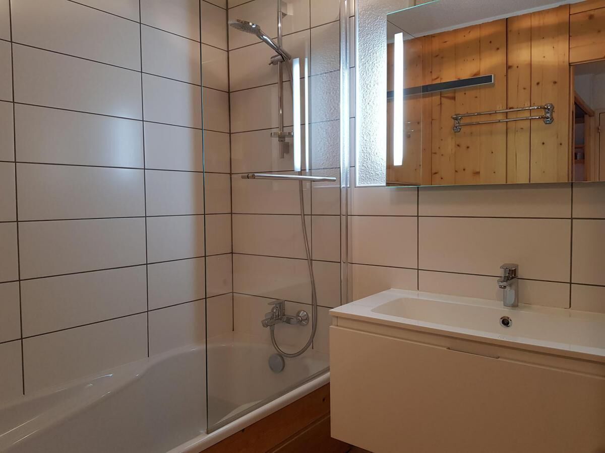 A bathroom with a glass-enclosed shower, a white sink, and wooden cabinets.