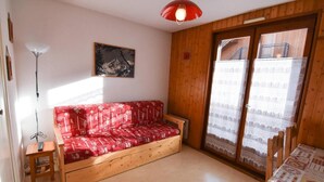 A cozy room with a wooden sofa, a small table, and a red pendant light. - 230m from ski slopes, 2nd floor, balcony, tv, ski locker, 22m², Valloire (Valloire)