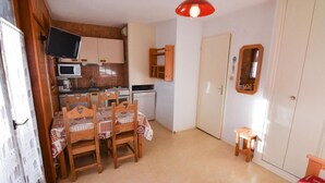 A compact kitchen with a microwave, stove, and a TV mounted on the wall. - 230m from ski slopes, 2nd floor, balcony, tv, ski locker, 22m², Valloire (Valloire)