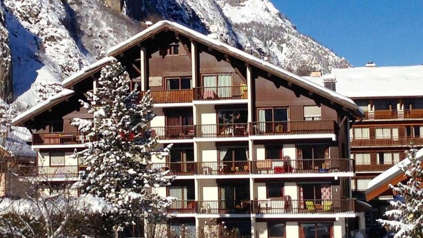 Ein mehrstöckiges Hotel mit Balkonen und einer Bergkulisse.