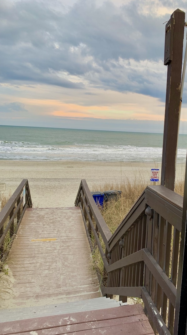 A wooden staircase leading to a beach with a 'Keep Off Dunes' sign.