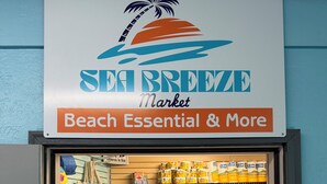 Un magasin appelé « Sea Breeze Market » affiche une enseigne indiquant qu’il vend des articles essentiels pour la plage et d’autres produits.