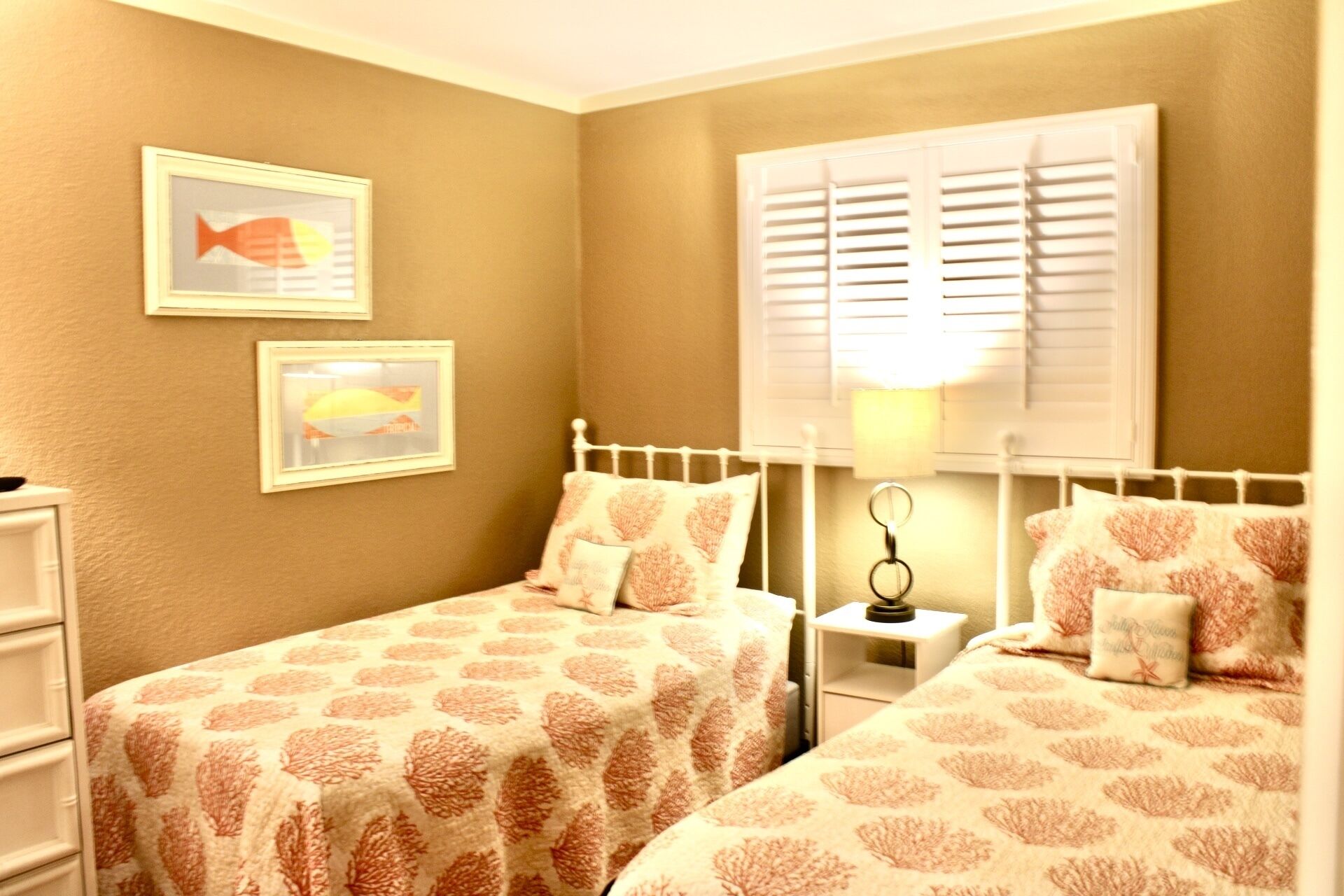 Ein Schlafzimmer mit zwei Betten, einem Nachttisch, einer Lampe und zwei gerahmten Bildern an der Wand.