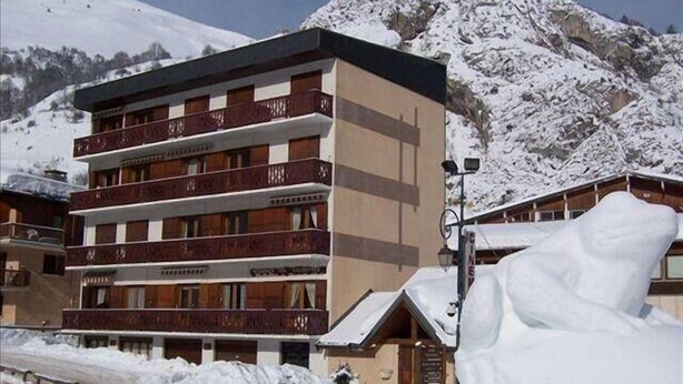 A multi-story hotel with balconies and a mountain backdrop. - Resort center, 1st floor, balcony, parking, tv, ski locker, 31m², Valloire (Valloire)