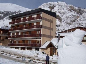 Een hotel met meerdere verdiepingen, balkons en een berg op de achtergrond.
