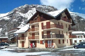 Un edificio a più piani con balconi, sullo sfondo di montagne.