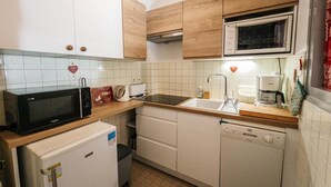 Eine kleine Küche mit weißen Schränken, einer Mikrowelle, einem Toaster, einem Spülbecken und einer Kaffeemaschine.