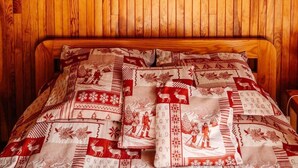Ein Zimmer mit Holzwänden und einem Bett mit einem gemusterten Überwurf.