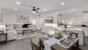 Un salon moderne avec un canapé, une table basse et un coin repas aménagé pour quatre personnes.