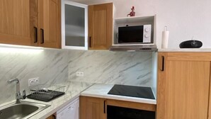 A compact kitchen with wooden cabinets, a microwave, a dishwasher, and a black countertop. - 50m from ski slopes, 3rd floor, balcony, tv, ski locker, 27m², Valloire (Valloire)