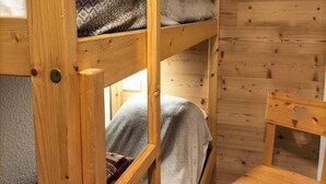 A bunk bed with a wooden frame, a small wooden chair, and a patterned blanket. - 50m from ski slopes, 3rd floor, balcony, tv, ski locker, 27m², Valloire (Valloire)