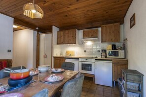 Une cuisine avec des meubles en bois, une table à manger pour quatre personnes et un four à micro-ondes.