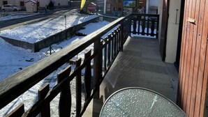 A balcony with a view of a snowy landscape and a building with a sign reading "MAGNIN Sports."