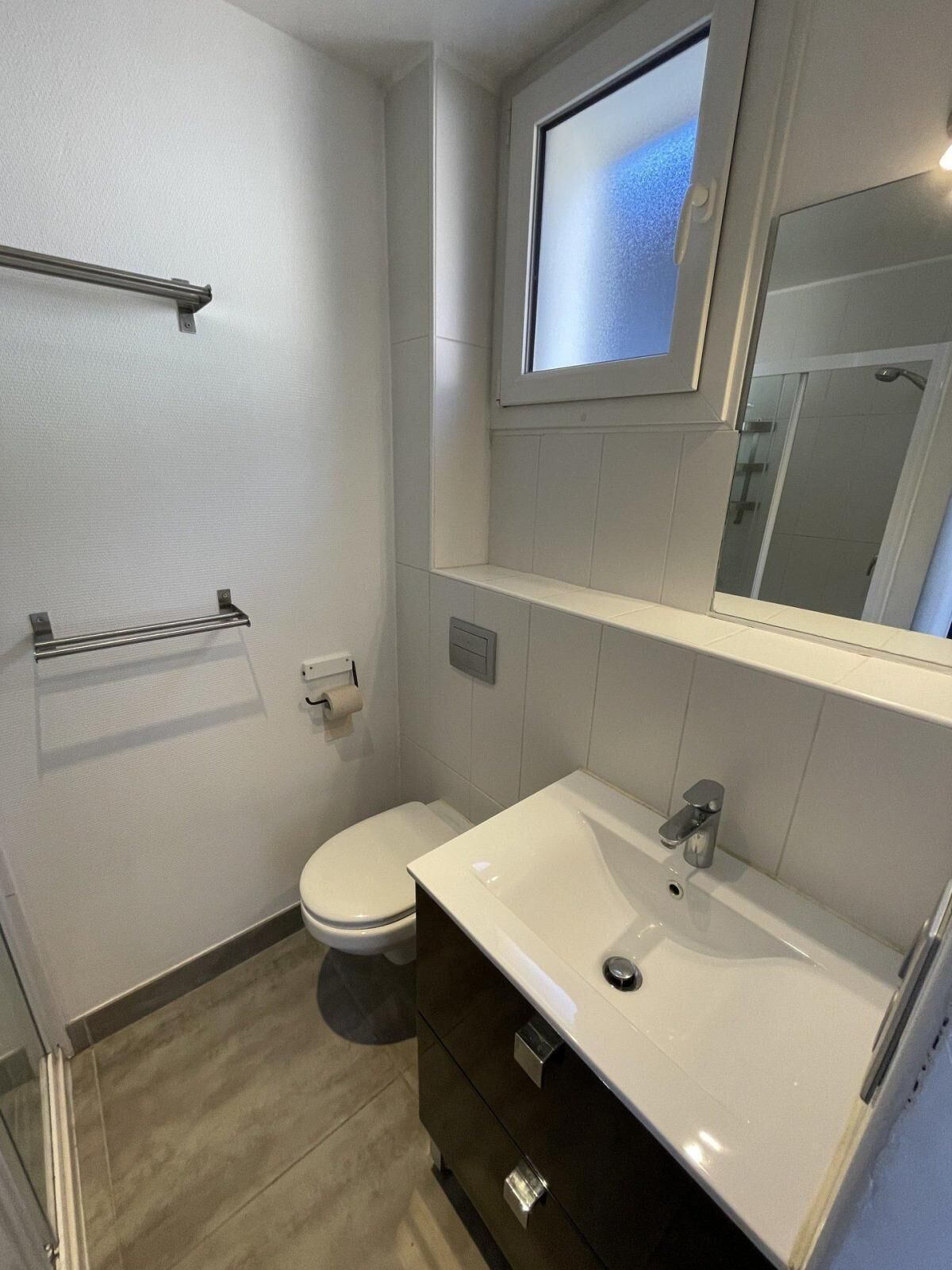 A modern bathroom with a toilet, sink, and mirror.