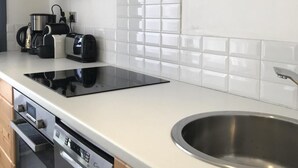 Ett modernt kök med en diskho i rostfritt stål, en inbyggd ugn och en diskmaskin.