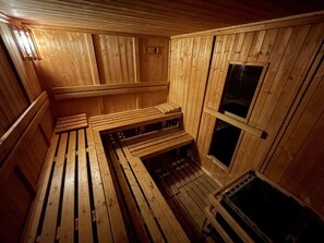Una sauna con bancos de madera y suelo inclinado, paredes de madera y una ventana.