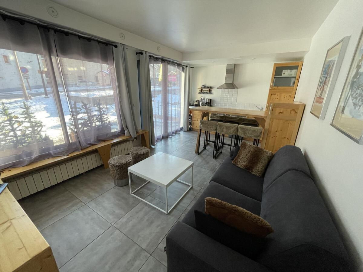 A modern living room with a sofa, a coffee table, and a dining area with a kitchen in the background.