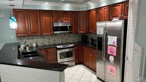 A modern kitchen with wooden cabinets, stainless steel appliances, and a tiled backsplash. - Luxury Penthouse 4BR Condo - Great for Families! (North Myrtle Beach)