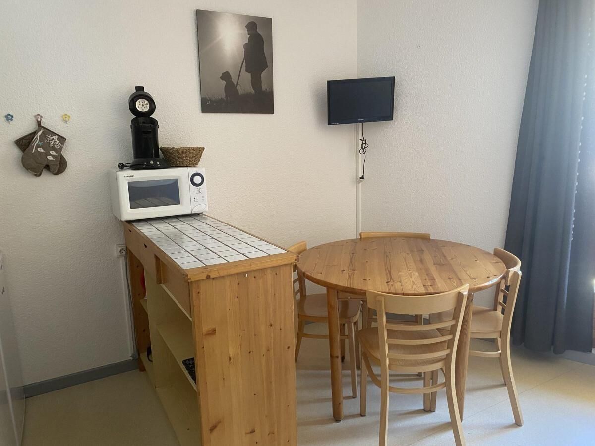 Une petite pièce comprenant une table et des chaises en bois, un four à micro-ondes, un téléviseur et un tableau encadré accroché au mur.