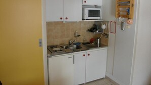 A compact kitchen with white cabinets, a microwave, and a sink.